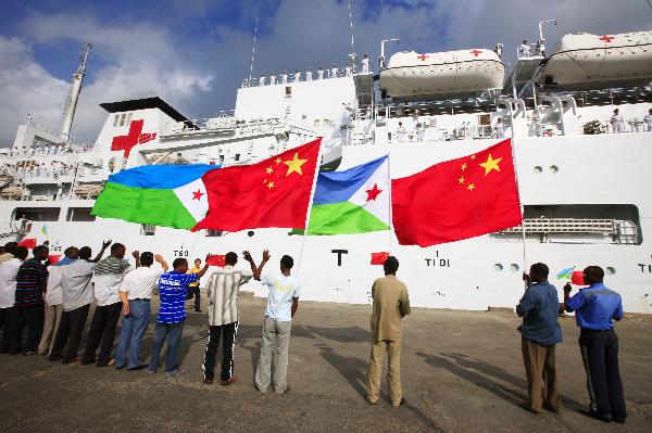 People wave national flags of China and Djibouti in front of China's hospital ship Peace Ark at the port of Djibouti, Sept. 29, 2010.