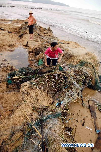 Local residents clear up remains of boats and nets on a beach in Lingshui County, south China&apos;s Hainan Province.