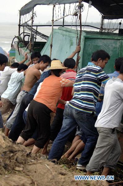 Local residents try to move a fishing boat neaped on a beach in Lingshui County, south China&apos;s Hainan Province.