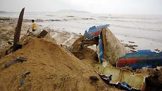 Photo taken on Oct. 6, 2010 shows remains of a fishing boat shattered by heavy rains and waves on a beach in Lingshui County, south China's Hainan Province.