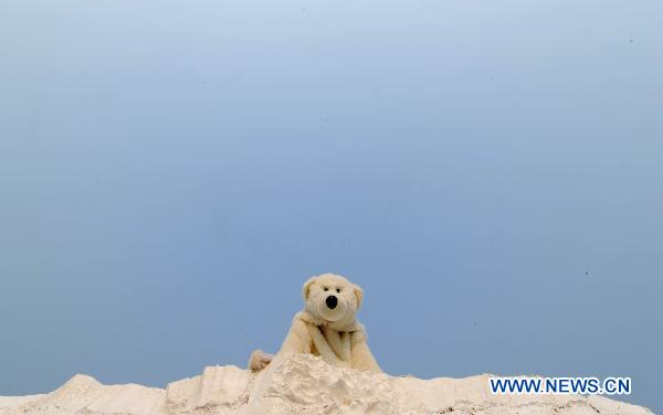 A Green Peace volunteer dressed in polar bear costumes is seen on an iceberg model on the square in front of the Tianjin Meijiang Convention and Exhibition Center, the venue of the UN Climate Change conference in north China's Tianjin Municipality, Oct. 7, 2010.