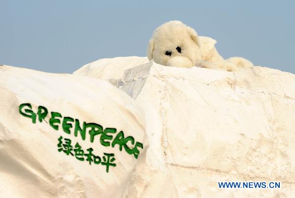 A Green Peace volunteer dressed in polar bear costumes is seen on an iceberg model on the square in front of the Tianjin Meijiang Convention and Exhibition Center, the venue of the UN Climate Change conference in north China's Tianjin Municipality, Oct. 7, 2010. 