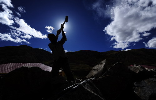 A worker wields a hammer near a newly-built house in Yushu County, northwest China's Qinghai Province, on Thursday Oct 7, 2010. 