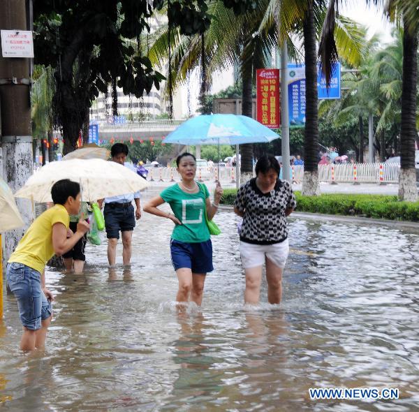  People walk on a water-flooded road after heavy rainfall in Haikou, capital of south China&apos;s Hainan Province, Oct. 8, 2010. 