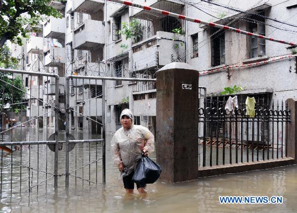 A woman walks in a water-flooded residence community after heavy rainfall in Haikou, capital of south China&apos;s Hainan Province, Oct. 8, 2010. 