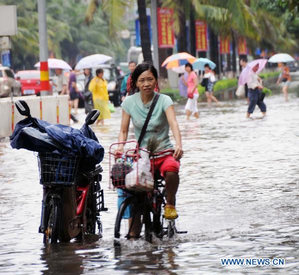 A woman rides on a water-flooded road after heavy rainfall in Haikou, capital of south China's Hainan Province, Oct. 8, 2010. 
