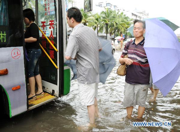 People wait at a water-flooded bus stop after heavy rainfall in Haikou, capital of south China's Hainan Province, Oct. 8, 2010. 