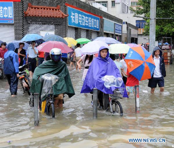 Residents pull themselves forward at a waterlogged street in Haikou, capital of south China&apos;s Hainan Province, Oct. 8, 2010.