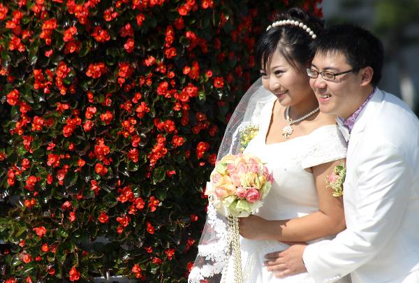 A newly-married couple pose for wedding photos at a park in Weihai, east China's Shandong Province, Oct. 10, 2010. Numerous young lovers across China got married on Oct. 10, 2010, or 10/10/10, hoping that the 'triple 10 day' will bring them good luck. In Chinese culture, many people believed that three '10's in a row means perfection.