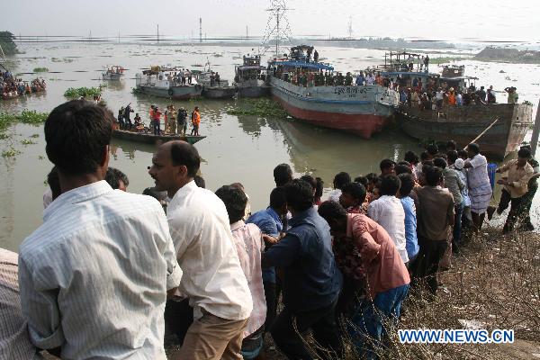 Local people hold the rope to help make the cargo vessel stable enough to pull the sunken bus out of the river in Savar, the suburbs of Dhaka, capital of Bangladesh, Oct. 12, 2010. 