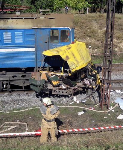A firefighter stands near the wreckage of a bus and the covered bodies of victims (R) after a collision in Ukraine's Dnipropetrovsk region October 12, 2010. [Xinhua]