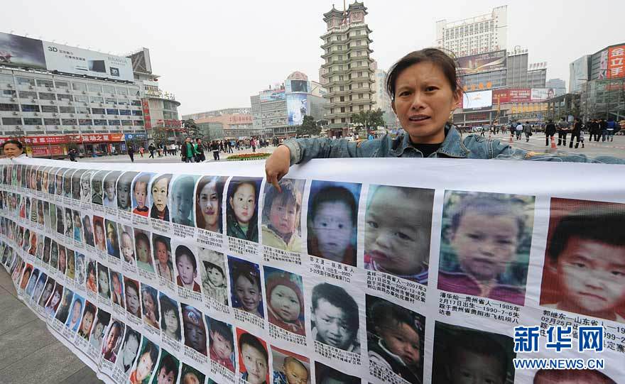 A mother of a missing child points at her missing child&apos;s photo in Erqi Square in Zhengzhou, Henan Province. The banner of more than 2,000 missing children’s photos was made by Feng Jianlin of Taiyuan, Shanxi Province, whose own daughter disappeared in 2008. 