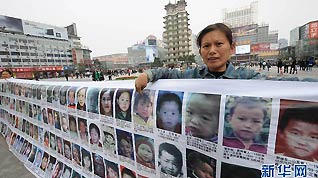 A mother of a missing child points at her missing child's photo in Erqi Square in Zhengzhou, Henan Province. The banner of more than 2,000 missing children’s photos was made by Feng Jianlin of Taiyuan, Shanxi Province, whose own daughter disappeared in 2008.