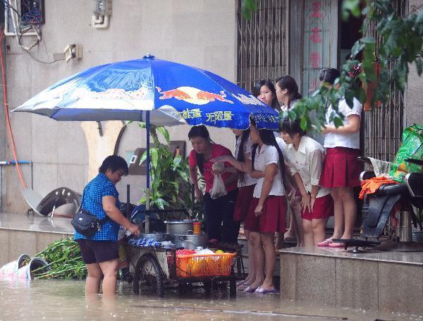 A pedlar works on the rain flooded street in Qionghai, south China's Hainan Province, Oct. 17, 2010. Heavy rainfall hit Qionghai again on Sunday.