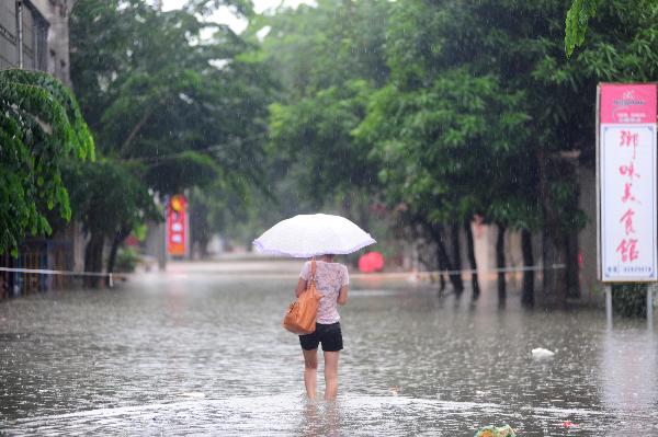 A woman walks on the flooded street in Qionghai, south China's Hainan Province, Oct. 17, 2010. Heavy rainfall hit Qionghai again on Sunday. 