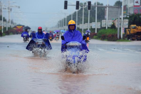 People ride on the flooded street in Qionghai, south China's Hainan Province, Oct. 17, 2010. Heavy rainfall hit Qionghai again on Sunday. 