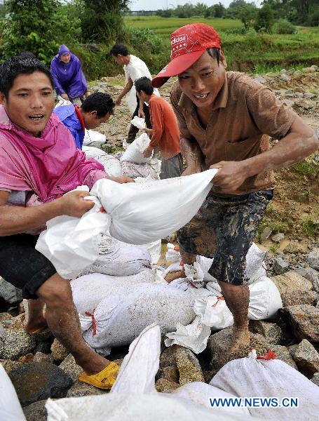 People carry sandbags to consolidate the dyke of Zhuli reservoir in Lingshui, south China&apos;s Hainan Province, Oct. 18, 2010. 