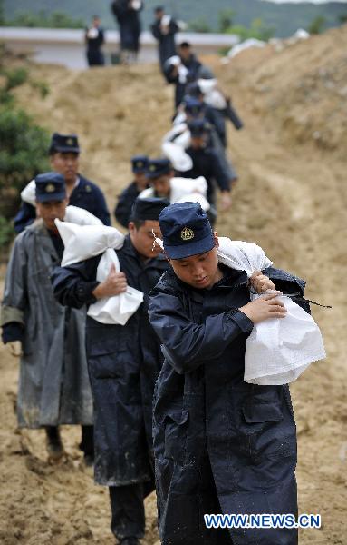 Soldiers carry sandbags to consolidate the dyke of Wanzhouling reservoir in Lingshui, south China&apos;s Hainan Province, Oct. 18, 2010. 