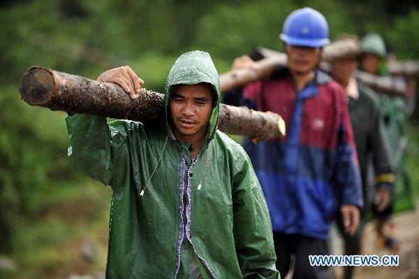 People carry wooden piles to consolidate the dyke of Zhuli reservoir in Lingshui, south China&apos;s Hainan Province, Oct. 18, 2010. 