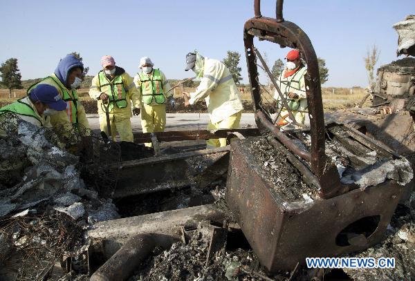 Workers clean the area near the remains of a bus and another vehicle in San Luis Potosi, outside Queretaro, Mexico, on Oct. 18, 2010. 