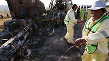 Workers clean the area near the remains of a bus and another vehicle in San Luis Potosi, outside Queretaro, Mexico, on Oct. 18, 2010.