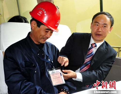 Hao Heng (L), service manager of China SANY Corporation, returns home and displays the red passport from Chile that allowed him to enter the core rescue site. Oct. 19th, 2010. 