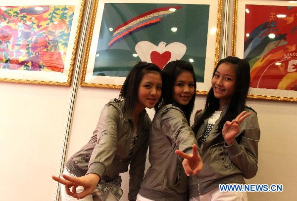 Gilrs pose for photos while visiting a picture exhibition celebrating the 65th UN Day in Beijing, capital of China, Oct. 25, 2010.