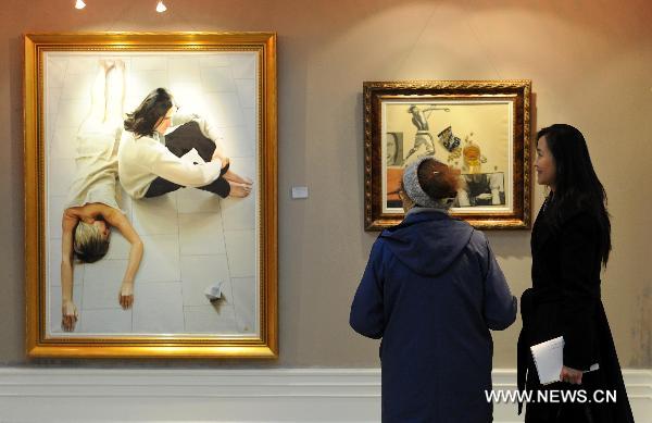 Visitors watch paintings in Harbin, northeast China's Heilongjiang Province, on Oct. 26, 2010. The exhibition showed works of seven painters from China and Russia. 