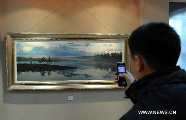 A visitor watches paintings in Harbin, northeast China's Heilongjiang Province, on Oct. 26, 2010. The exhibition showed works of seven painters from China and Russia. 
