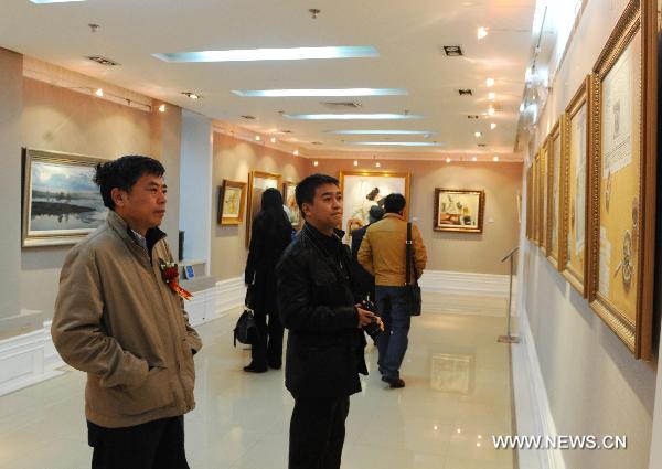 Visitors watch paintings in Harbin, northeast China's Heilongjiang Province, on Oct. 26, 2010. The exhibition showed works of seven painters from China and Russia.