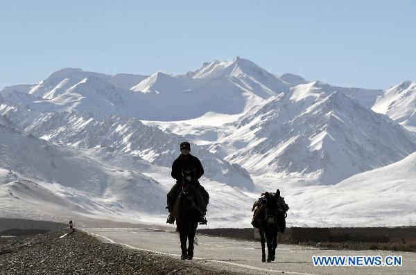 A herdsman of Tajik ethnic group rides on a road on the Pamirs in northwest China's Xinjiang Uygur Autonomous Region, Oct. 23, 2010. 