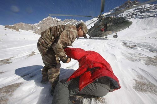 A rescuer help two stranded engineers to walk for the helicopter during a rescue in Tianshan Mountains area near Baicheng county of Aksu prefecture in northwest China's Xinjiang Uygur Autonomous Region, Oct 27, 2010. 