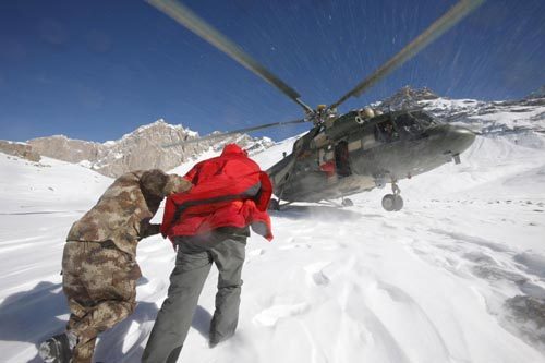 A rescuer help two stranded engineers to walk for the helicopter during a rescue in Tianshan Mountains area near Baicheng county of Aksu prefecture in northwest China's Xinjiang Uygur Autonomous Region, Oct 27, 2010. 