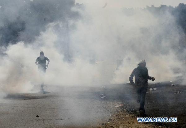 A protester runs through tear gas thrown by Israeli riot police during clashes in Umm el-Fahm Oct. 27, 2010. 