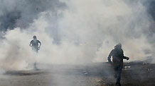 A protester runs through tear gas thrown by Israeli riot police during clashes in Umm el-Fahm Oct. 27, 2010.