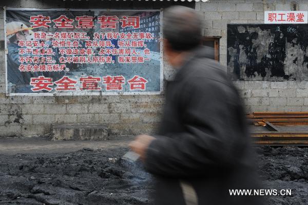 A worker walks past a poster with the slogan reminding the safety in production outside the flooded Dapo coal mine in Machang Town of Puding County under Anshun City, southwest China&apos;s Guizhou Province, Oct. 28, 2010. 