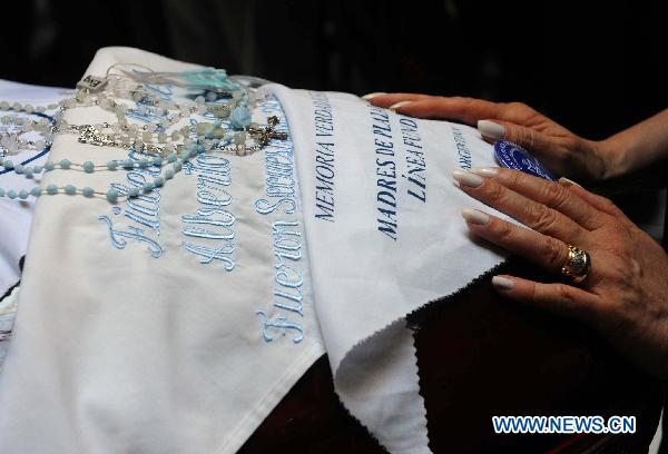 In this handout image provided by the Argentine presidency, Argentine President Cristina Fernandez de Kirchner touches handkerchief given by human rights group Madres de Plaza de Mayo, placed on the coffin of her late husband, former President Nestor Kirchner, during his wake in the Presidential Palace in Buenos Aires, Argentina, on Oct. 28, 2010.