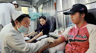 Students from Peking University donate blood at a mobile blood collection station in Beijing Sunday. In response to a recent low blood inventory at hospitals in Beijing, a number of college students in the city have donated blood. Shandong, Shanxi and Jiangxi provinces, as well as Changchun in Jilin Province, are also suffering acute blood shortages.