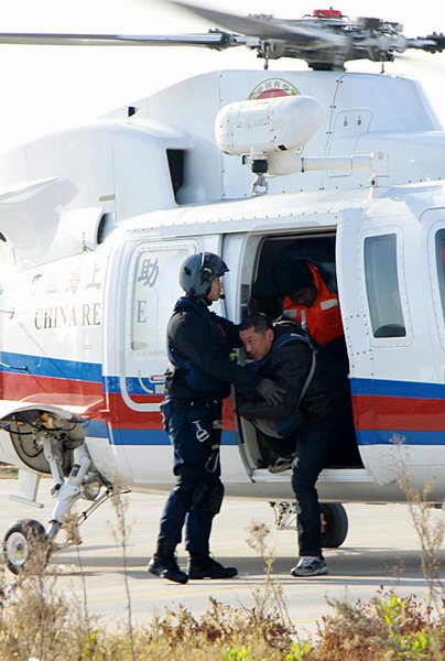 Rescued crew members of a stranded freighter walk out of a helicopter with the help of rescue workers at a parking lot in Weihai, east China&apos;s Shandong Province, Nov 2, 2010. 