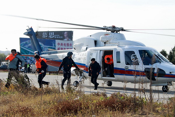 Rescued crew members of a stranded freighter walk out of a helicopter with the help of rescue workers at a parking lot in Weihai, East China&apos;s Shandong province, Nov 2, 2010. [Xinhua]