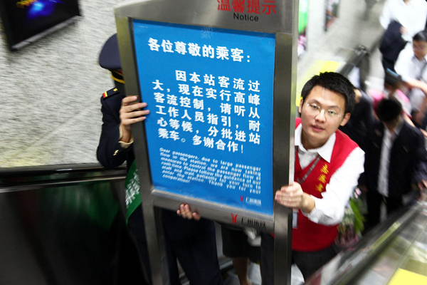 Volunteers put up a traffic control notice at the entrance of the Gangding subway station in Guangzhou on Monday.