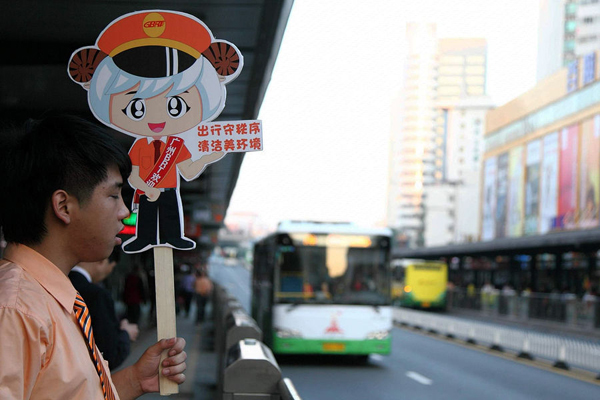 A public transportation worker guides passengers onto buses at a BRT platform in Guangzhou on Monday.