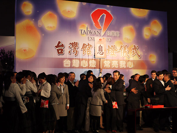 Staff members of Taiwan Pavilion embrace after the lights of the pavilion were turned off Sunday night. 