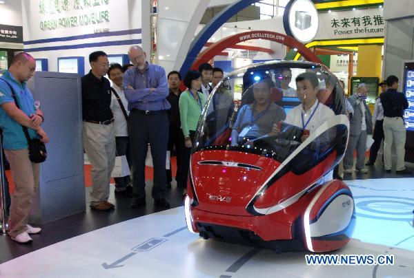 Visitors try a concept electric vehicle made by the General Motors during the 25th World Battery, Hybrid and Fuel Cell Electric Vehicle Symposium and Exposition in Shenzhen, south China's Guangdong Province, Nov. 7, 2010. 
