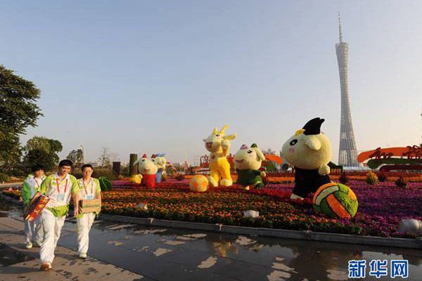 Volunteers walk past sculptures of the Asian Games mascots known together as &apos;Xiang He Ru Yi Le Yangyang&apos; on Haixinsha Island, the site for the opening ceremony of the games in Guangzhou, southeast China&apos;s Guangdong Province, Nov.8, 2010. 