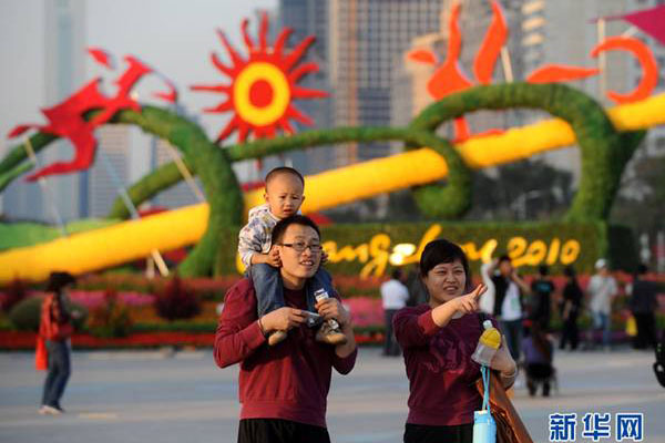 A family walks past Guangzhou&apos;s Asian Games themed landscape in southeast China&apos;s Guangdong Province, Nov.8, 2010. Guangzhou has dressed up itself with flowerbeds, sculptures and mascots to embrace the upcoming grand festival.