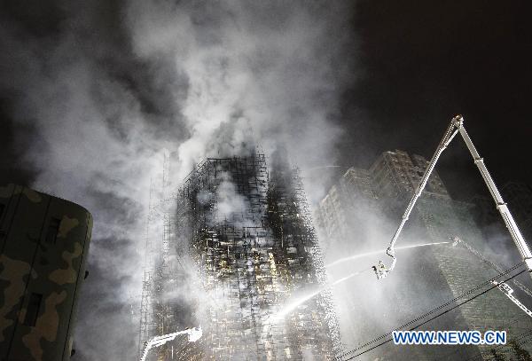 Firefighters extinguish blaze on the apartment building on fire in the downtown area of Shanghai, east China, Nov. 15, 2010.