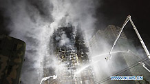 Firefighters extinguish blaze on the apartment building on fire in the downtown area of Shanghai, east China, Nov. 15, 2010.