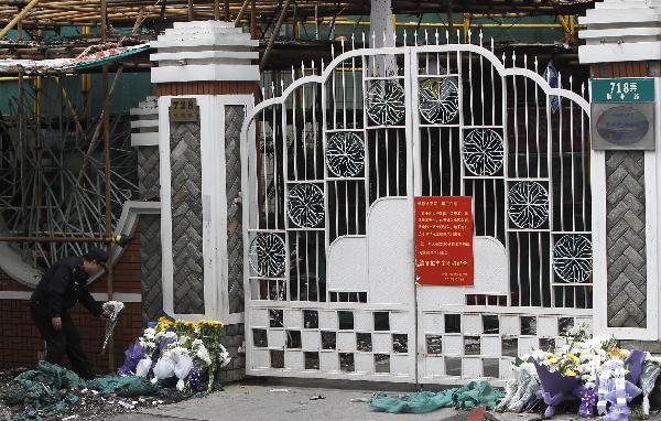 Flowers are laid at the entrance of the burned residential building in Shanghai, east China, Nov. 16, 2010. The death toll of a big fire that engulfed the high-rise building in downtown Shanghai had risen to 53 by 9:30 a.m. Tuesday, local authorities said. [Xinhua]