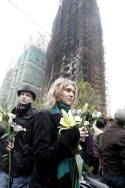 Russian students present flowers to the accident site to mourn for fire victims in Shanghai, east China, Nov. 16, 2010. The death toll of a big fire that engulfed the high-rise building in downtown Shanghai had risen to 53 by 9:30 a.m. Tuesday, local authorities said. [Xinhua]